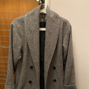 grå kappa - en grå mönstrad kappa från h&m. den är bara använd någon enstaka gång men den kommer aldrig till användning för mig längre.