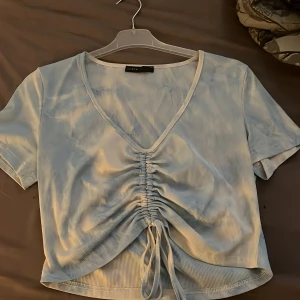 Topp - Blå vit tröja med u-ringning som man kan göra större eller mindre. Storlek L men passar även M