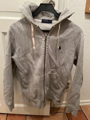 Ralph lauren zip hoodie grå - Ralph lauren grå zip hoodie i storlek S, hoodien är i bra skick och har används 2-3 gånger, inga skavanker eller skador.