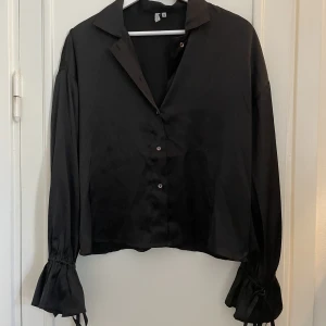 Satinskjorta med detalj - Svart satinskjorta från Nelly, fin detalj i ärmslut. 