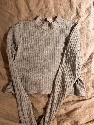 Grå croppad långtröja - En lätt croppad grå tröja som är ribbad. Använt 2 gånger och är i väldigt bra skick utan fläckar:)