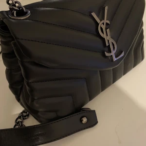 Ysl väska - Säljer min fina ysl liknande väska, den är i nyskick då den aldrig har kommit till användning. ❤️ den har väldigt många fina detaljer som gör att den ser äkta ut😊 kontakta för mer info ❤️lite plastig kedja och måtten är 23cm bred & 18cm hög