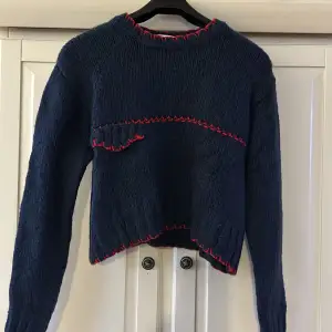 En kortare stickad tröja från zara i färg marinblå med röda detaljer, storlek S