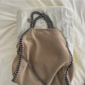 Stella McCartney väska - Säljer min Stella McCartney falabella väska i beige. Superfint skick och dustbag mm tillhör. Pris kan diskuteras men det ska va rimligt. Inget är oxar förens man betalat. Kan mötas i Stockholm ❤️