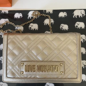 Väska från Moschino - Säljer min guldiga väska från Moschino. Den är i jättebra skick. ✨🫶🫶