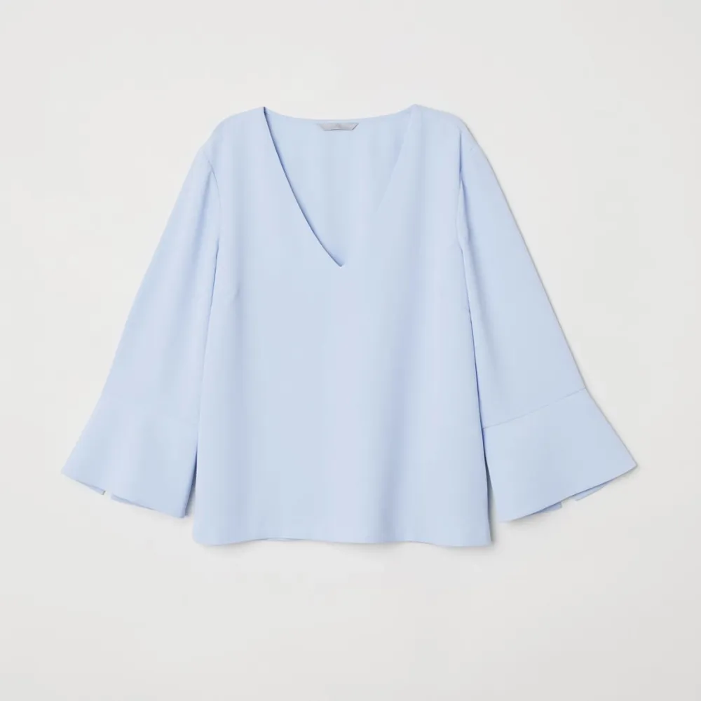 Märke: H&M Vad: En v-ringad blus i vävd kvalitet. Blusen har trekvartslång trumpetärm med slits. Storlek: 36 Upplevd i storlek: Normal Färg: Ljusblå Material: 100% polyester  Skick: Inget att anmärka på. Blusar.