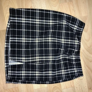 Kort kjol - Kort svart kjol med en slut där framme och vita linjer 