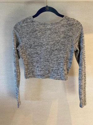 Tröja  - Grå tight och stretchig långärmad tröja med en u ringning. Arm längd på 45 cm och längd på 20 cm från armhålan 