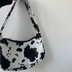 Väska  - Väska i komönstrat mönster. Köpt här på plick för 2 år sedan men har aldrig använt. Nyskick!