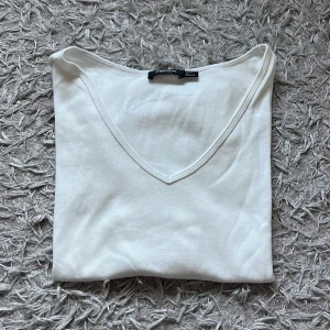 Vit t-shirt med detaljer -  En vit t-shirt med små blomm detaljer