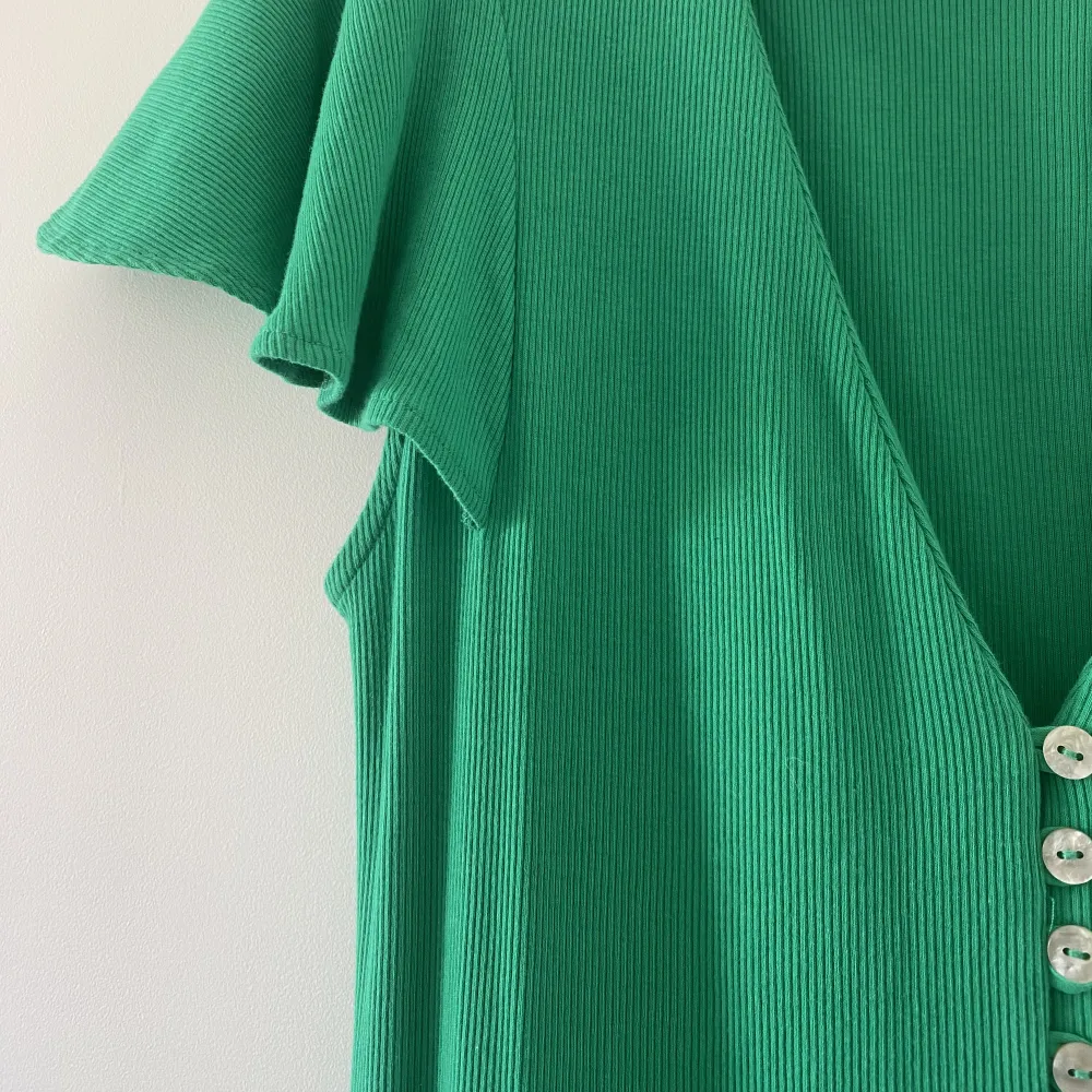 Långklänning i härlig grön kulör från Zara! Knäppning längs hela framsidan som sedan skapar en vacker slit nedtill. Volanger som lägger sig fint över axlarna. Klänningar.