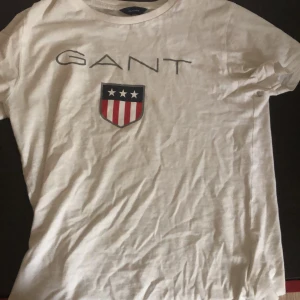 Gant T-Shirt  - Jag köpte denna och den har växt ut. Den är vit och har gant över bröstet. Priset kan sänkas. Ha en bra dag! 