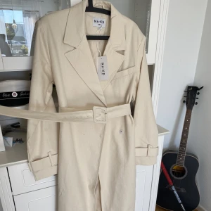 Trenchcoat - Helt oanvänd med lappen kvar. Rätt tunn så passar bra på vår/höst/sommarkvällar! Storlek 38 och inget konstigt med storleken. :) pris på nakd är 899 kr 