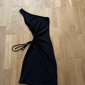 Klänning  - Väldigt fin svart klänning med öppning på ena sidan passar väldigt fint för semestrar, har aldrig använt, storlek xs