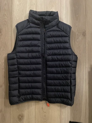 Väst  - Lite tjockare väst ifrån Save The Duck. Väldigt bra skick! Västen är i storlek L och kommer tillsammans med en liten påse man kan packa ner den i. Färg mörk blå och passar perfekt över en tröja eller under en jacka. 