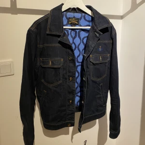 Vintage Vivienne westwood jeansjacka - Säljer en vintage mörkblå vivienne westwood jacka i storlek L. Passformen är ganska liten, skulle säga det är mer en strl M. Sparsamt använda! Inga hål eller andra stora fel. Skriv för mer info eller vid funderingar🤙🏼