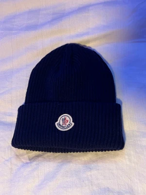 Moncler mössa - Säljer en Moncler mössa som jag köpte förra hösten men har ej använt den då jag känner att mitt huvudform inte passade. köpte den på NK i Stockholm. Nypris: 2000kr, mitt pris 800kr. Finns i Stockholm, kan både fraktas och mötas.