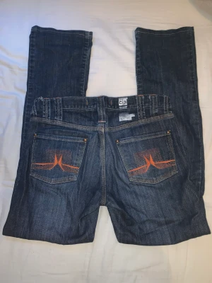 lågmidjade jeans - Säljer dessa lågmidjade jeans med skitsnygg orange detalj i sömmarna! Tyvärr för lång för att ha de.  Midjemått 38cm tvärs över, innerbenslängd 70cm