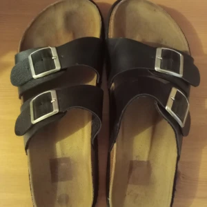 Svarta tofflor - Säljer ett par svarta tofflor som är relativt använda och sulorna har gått upp, men jag har limmat ihop dem och det har inte uppstått igen. Vet inte riktigt vad det är för storlek, men skulle nog gissa på 39,5/40. 