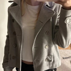 GRÅ KAPPA/JACKA - Knappast använd super bra skick , har innerfickor. 75% ull , 20% polyester, 5% kashmir. Pruta på