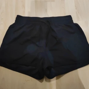 Svarta Badshorts - Enkla svarta Badshorts, har använts över bikini trosor. Kan användas som vanliga shorts också men har badshorts materialet.