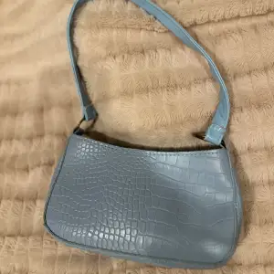 En oanvänd babyblå väska med krockodilmönster