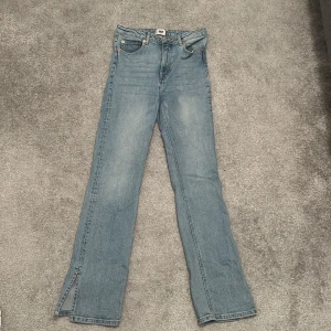 Blåa jeans med split ends  - Dessa blåa jeans har en öppning precis vid slutet av byxan på båda sidorna, byxan är i bra skick men har en liten skada där en blå tråd i byxan syns. Använda ett fåtal gånger 