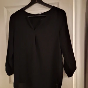 Blus - Blus som aldrig är använd, v ringat framtill och knappar i ärmarna