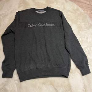 Mörkgrå tröja från Calvin Klein i nyskick. Storlek M där passformen är något loose.