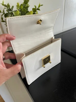 Liten väska - Liten oanvänd väska från åhléns med guldknapp. 