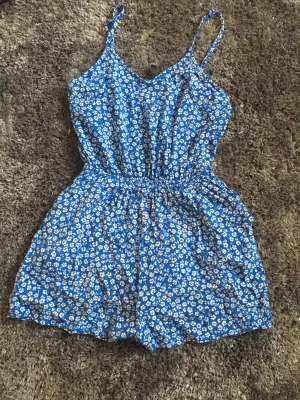 Blommig byxdress - Super gullig byxdress. Använt skick men inga tydliga defekter. Den är förliten på mig därav inga bilder på.Vid intresse kontakta mig. Plagget tvättas innan postning. 