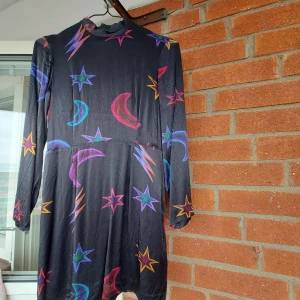 Svart glansig klänning - Svart längre klänning i polyester. Storlek 36.  Ursprungligen från H&M, aldrig använd, i mycket gott skick.