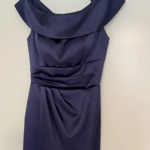 balklänning - Klänningen är fullängd och marinblå, satin 💙den har en slits och är off shoulders. Endast använd en gång och är som ny! Den är i storlek 36 men är mindre och passar 32/34. Den har även inbyggd bh! Tvivla inte på att skriva för mer information/ bilder!