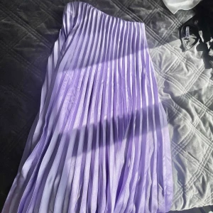Långkjol - Jättefin lång plisserad kjol i en pastell lila färg, i bra skick. Går strax över fötterna på mig som är 173. Resår i midjan så passar Xs och S