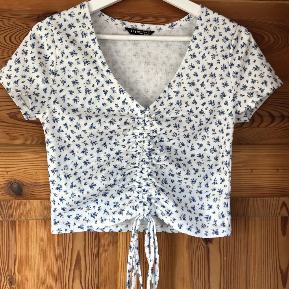 Sommar t-shirt med thight passform med små blåa blommor. Sparsamt använd, säljs då den inte kommer till användning. Frakten ingår i priset💛. Toppar.