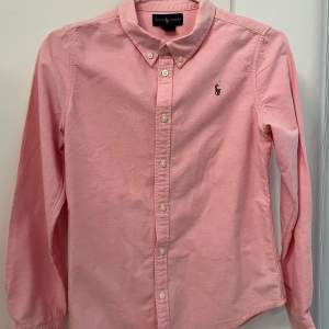 Rosa tjejskjorta från Ralph Lauren i fint skick. Storlek 14, men är liten. Jag skulle säga 10-12 år.