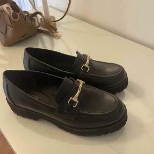 Loafers - Svarta loafers med guldspänne. Beställda ifrån asos, ifrån märket raid. Använda enstaka gånger🖤