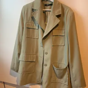 Militärgrön jacka med fickor och knappar. Är större i storlek.