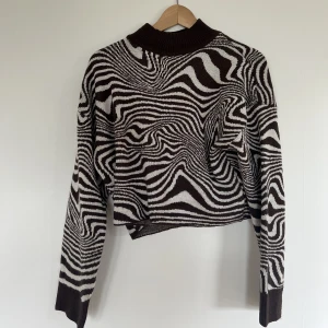 Stickadtröja - En brun/vit randig stickad croppad tröja med krage från H&M i storlek S. Använd ett få tal gånger men i nyskick. Får tyvärr ingen användning av den.
