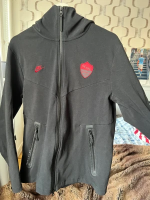 Nike tech fleece (Roma FC) - Säljer nu denna eftertraktade Nike tech fleece med de mäktiga laget Roma FC på. Tröjan är i ny skick, använd 2 gånger.