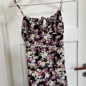 Sommarklänning  - Svart kort tunn sommarklänning med lila/gula blommor💛🌸💜