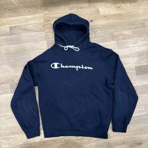 Mörkblå Champion hoodie i storlek Medium. Toppen av ena snöret har ramlat av.