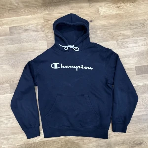 Champion hoodie - Mörkblå Champion hoodie i storlek Medium. Toppen av ena snöret har ramlat av.