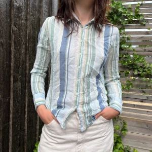 Randig Skjorta - Superfin och tunn sommarskjorta. En gammal favorit som har gjort sitt! Stl. 38. Den har en liten fläck i bak tyvärr men inget man tänker på.