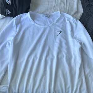 Träningströja - Vit luftig träningströja från gymshark, skönt material. Köpt från gymsharks egna hemsida, använd 1 gång. 