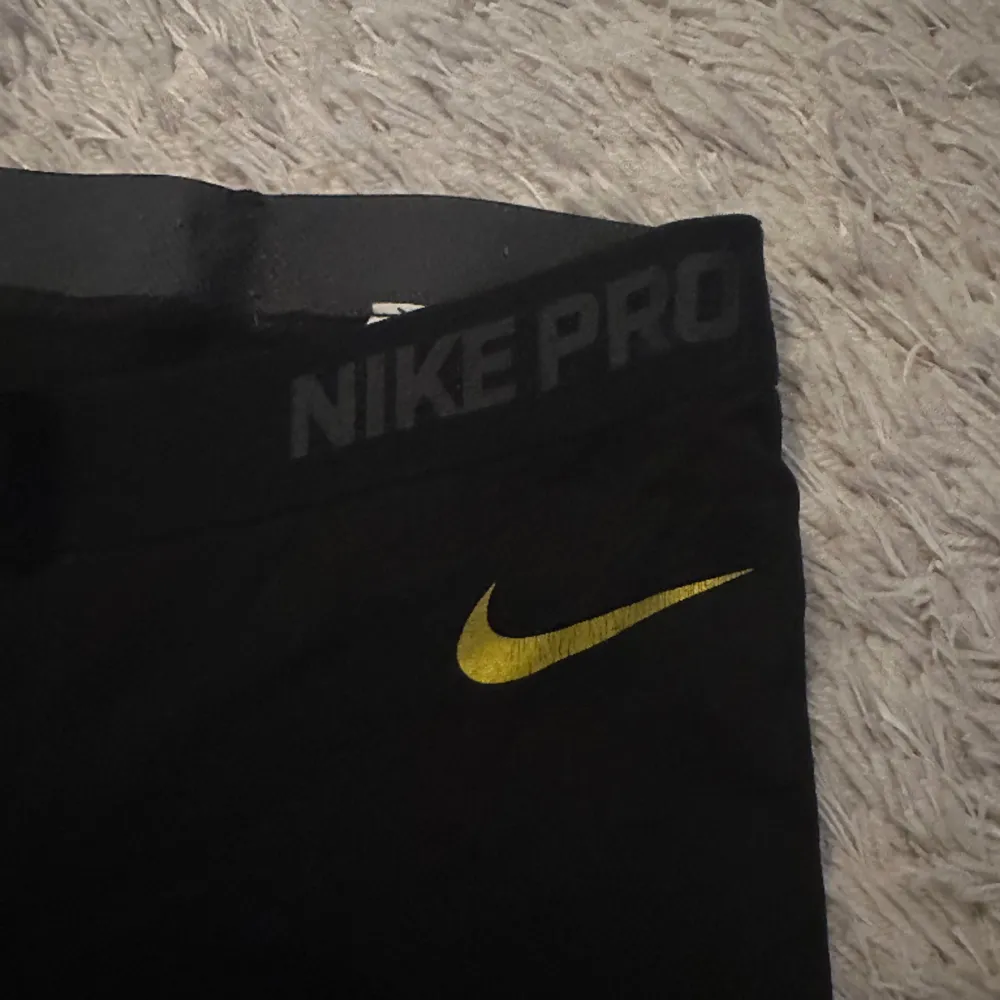 Säljer mina träningstights med guld detaljer från Nike  i storlek XS. De är i bra skick förutom att Nike märket har skavts av lite. Se bild 3. Skriv för funderingar.. Övrigt.