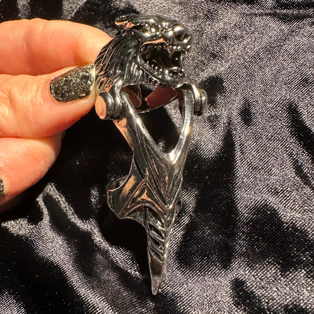 Så ovanlig och fet silverfärgad ring med varg och utsirad ledad ”klo”. Drygt 8 cm lång. Övre ringen 2,1 cm i innerdiameter. Nedre ringen 1,7 cm i innerdiameter. Helt ny. Uttagen enbart för fotografering. Stål. Ovanlig. Uppseendeväckande. Fynd.. Asusteet.