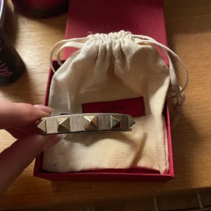 Valentino armband - Säljer mitt valentino armband! Köpt i Frankrike för ca 2 år sedan. Lite tecken på användning därav det billiga priset men annars i toppenskick med box, extra nitar osv kvar 💖nypris runt 2400🙌🏼 pris kan diskuteras vid snabbt köp