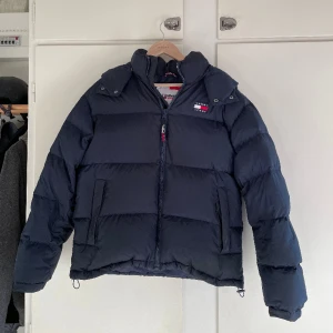 Tommy Hilfiger Alaska Puffer - Nu säljer jag min snygga jacka! Funkar extremt bra för vintern och även våren och hösten. Luvan sitter med knappar och man kan ta av. Har en liten defekt på vänstra sidan av ryggen men syns inte tydligt när den används. Skick 8/10. Nypris 2900kr