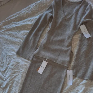 Glittrigt set som ger fin form - Fint glittrigt set som är skuret vid midjan (se bild) så man får en jätte fin form, tröjan har utsvängda ärmar. Strl S och är aldrig använt, prislappar kvar. Både kjolen och tröjan ingår, kostar annars 599kr var för sig.  Beige/grå färg
